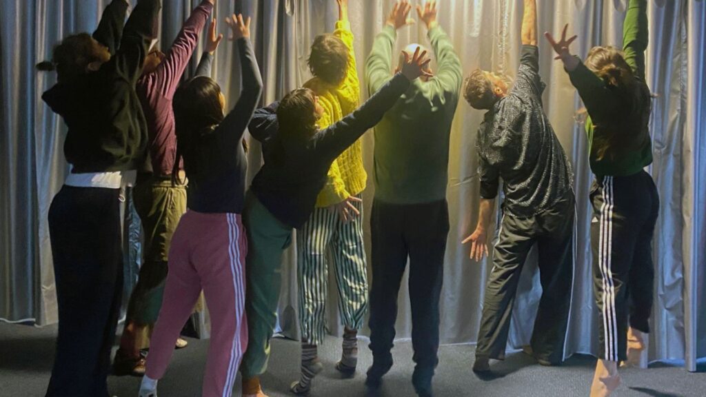 A group of people reaching their hands and arms up to towards the ceiling