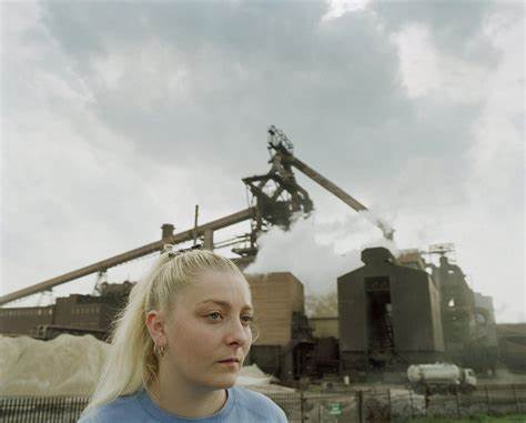 A young woman's profile with a factory behind her