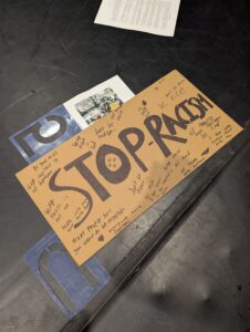 A cardboard protest sign that reads “Stop racism"